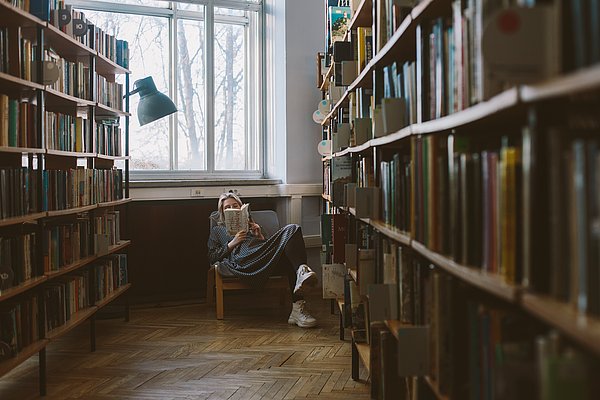 Studentin liest in der Bibliothek Gemütlich in der Universitötsbibliothek